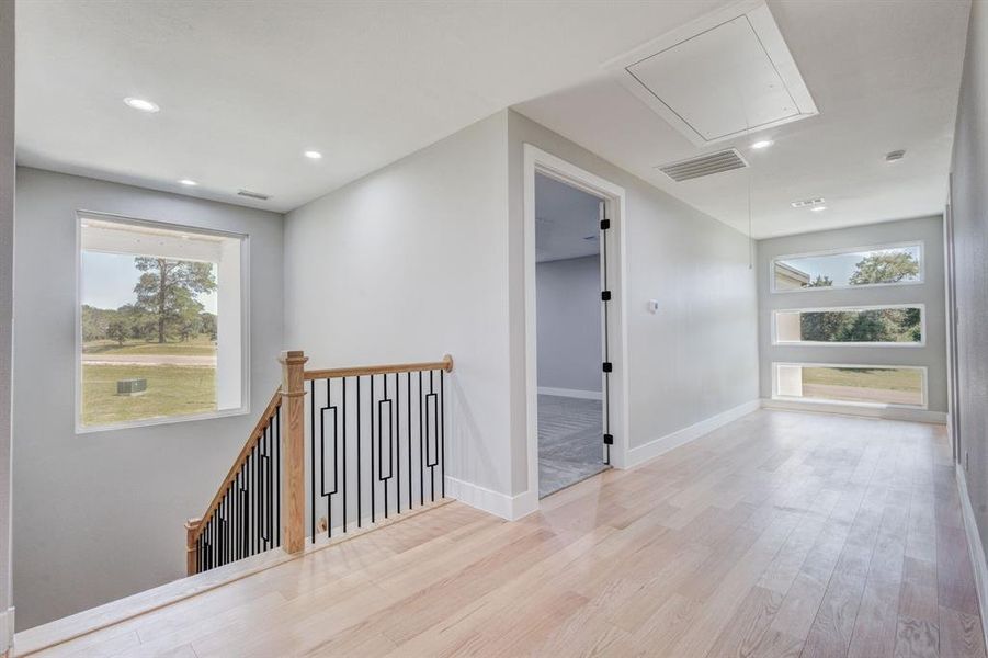 Upper-level hallway featuring light wood-finish flooring, recessed lighting, and white trim