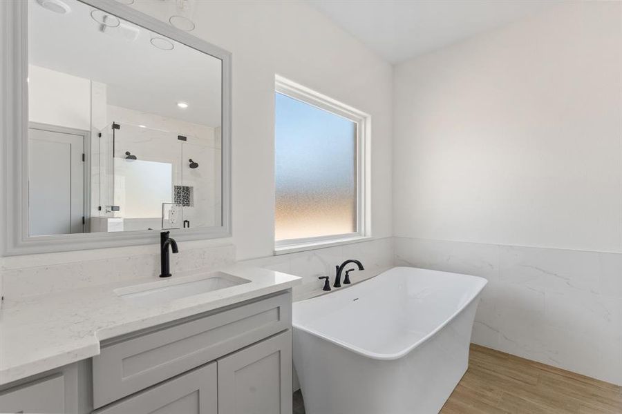 Bathroom with tile walls, a freestanding tub, light wood finished floors, a wainscoted wall, and a stall shower