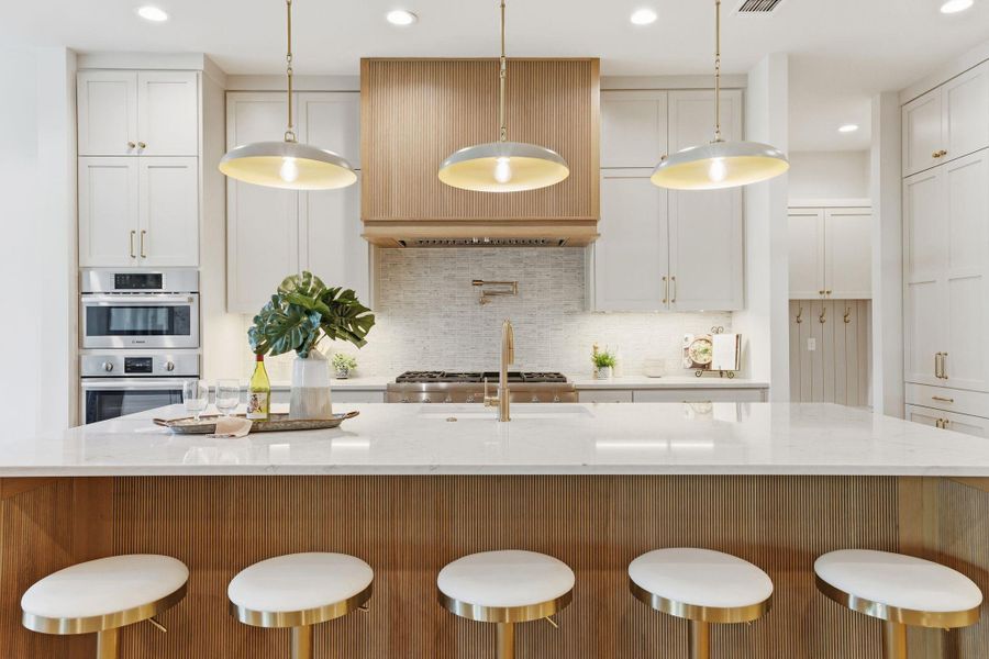 Kitchen with a breakfast bar area, recessed lighting, light stone countertops, hanging light fixtures, and white cabinets Kitchen with a breakfast bar area, recessed lighting, light stone countertops, hanging light fixtures, and white cabinets