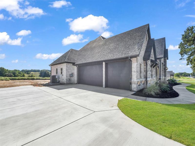 View of front of property with driveway, an attached garage, stone siding, and a front lawn