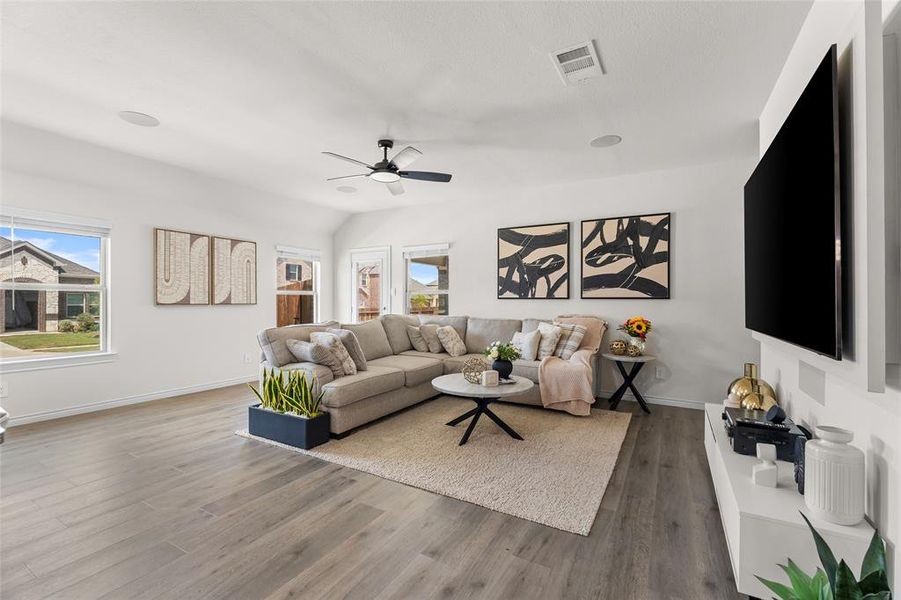 Living area featuring wood finished floors, plenty of natural light, a ceiling fan, and vaulted ceiling Living area featuring wood finished floors, plenty of natural light, a ceiling fan, and vaulted ceiling