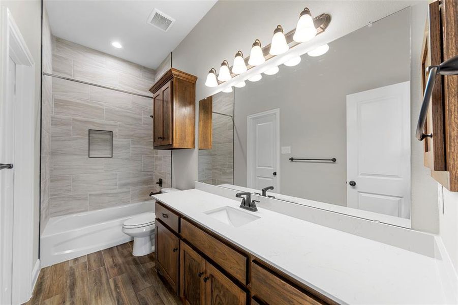 Full bathroom featuring vanity, toilet, wood finished floors, bathing tub / shower combination, and recessed lighting Full bathroom featuring vanity, toilet, wood finished floors, bathing tub / shower combination, and recessed lighting