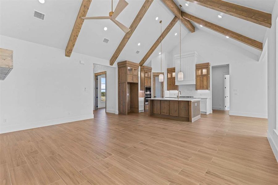 Unfurnished living room with high vaulted ceiling, wood finish floors, and beam ceiling