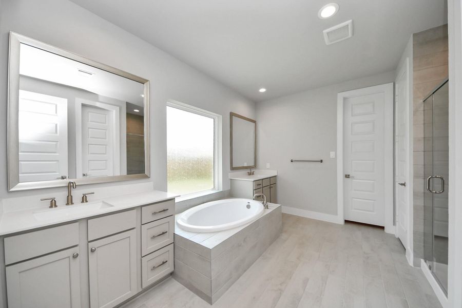Escape to a spa-like oasis in this primary bathroom. Enjoy a walk-in shower with tile surround, a separate garden tub with custom detailing, and an elegant vanity featuring light countertops, modern hardware, and beautiful recessed lights. Experience luxury and relaxation in every detail. Escape to a spa-like oasis in this primary bathroom. Enjoy a walk-in shower with tile surround, a separate garden tub with custom detailing, and an elegant vanity featuring light countertops, modern hardware, and beautiful recessed lights. Experience luxury and relaxation in every detail.