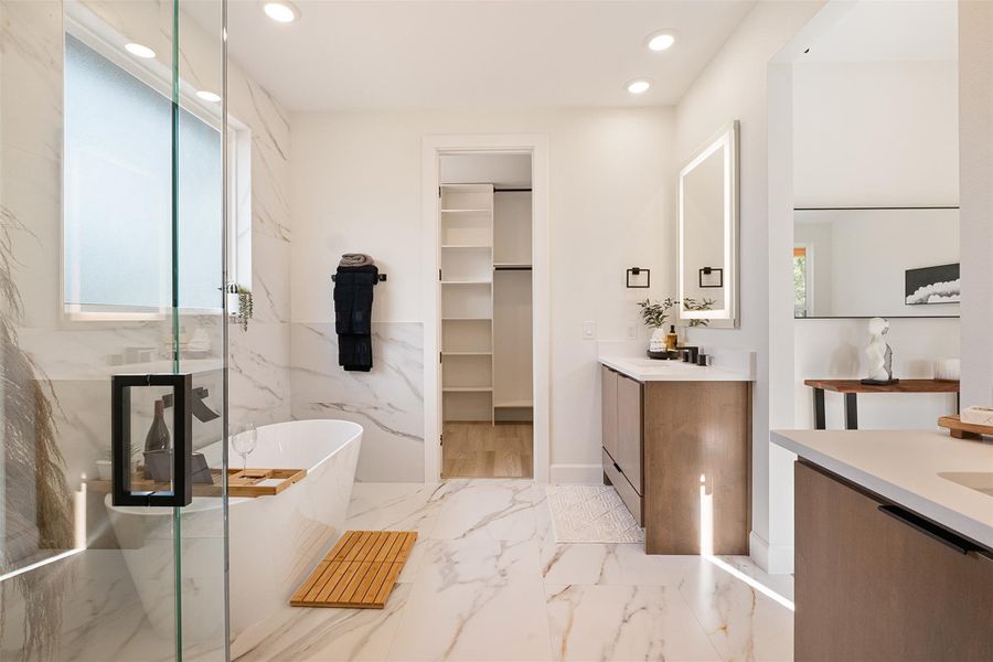 Full bath with recessed lighting, vanity, light marble finish flooring, a spacious closet, and a freestanding bath