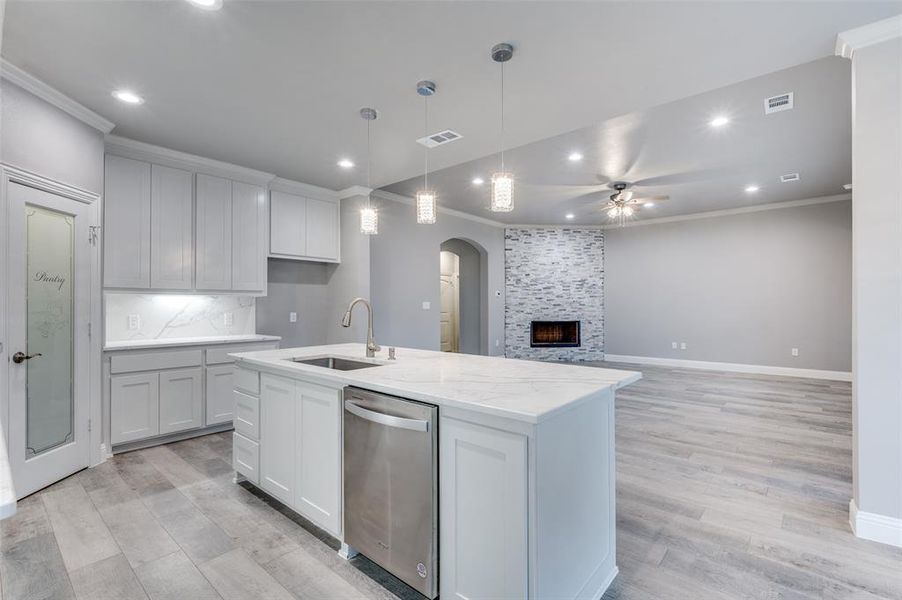 Kitchen featuring sink, white cabinets, dishwasher, and a center island with sink