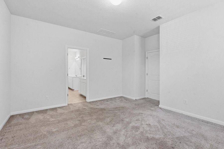 An inviting primary bedroom featuring soft carpet and direct access to a private bathroom. An inviting primary bedroom featuring soft carpet and direct access to a private bathroom.