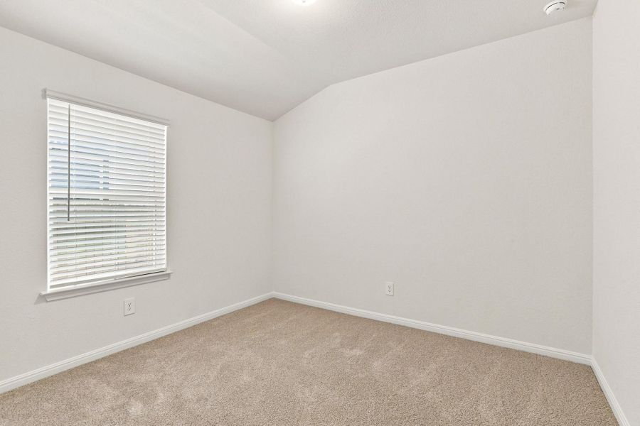 Plush carpeting and a large window with blinds define this versatile bedroom space.