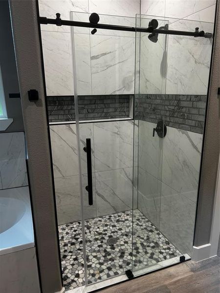 Bathroom with hardwood / wood-style floors and independent shower and bath