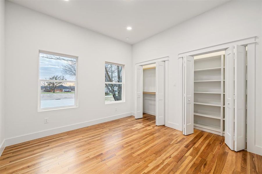 Unfurnished bedroom featuring recessed lighting, baseboards, multiple closets, and light wood-style flooring