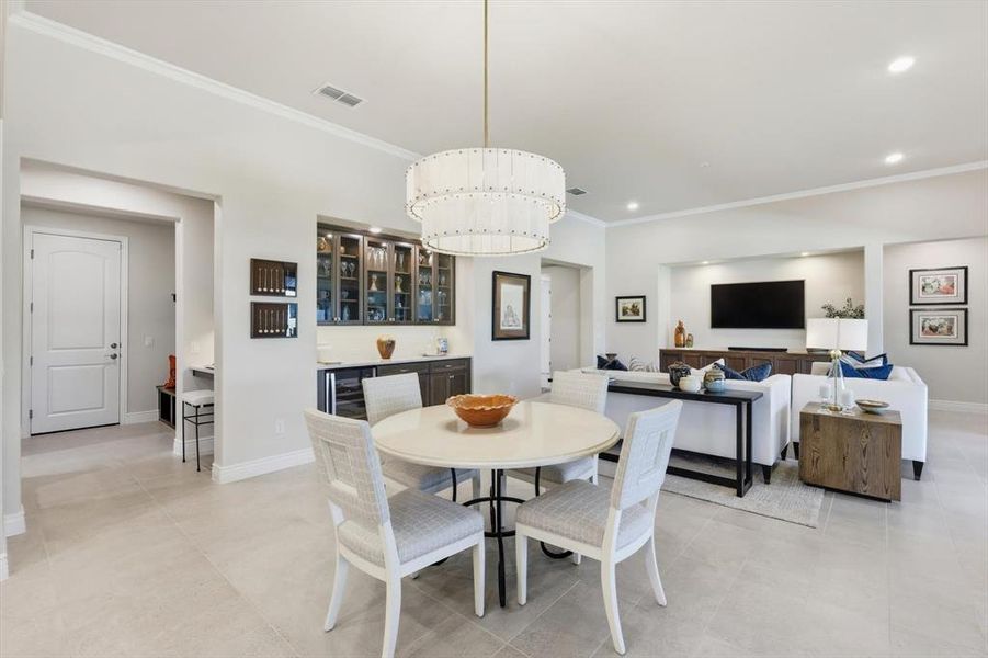 Dining room with crown molding, bar area, beverage cooler, light tile patterned flooring, and a chandelier