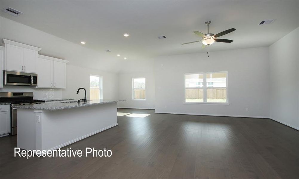 Kitchen featuring dark hardwood / wood-style floors, a kitchen island with sink, sink, white cabinets, and appliances with stainless steel finishes