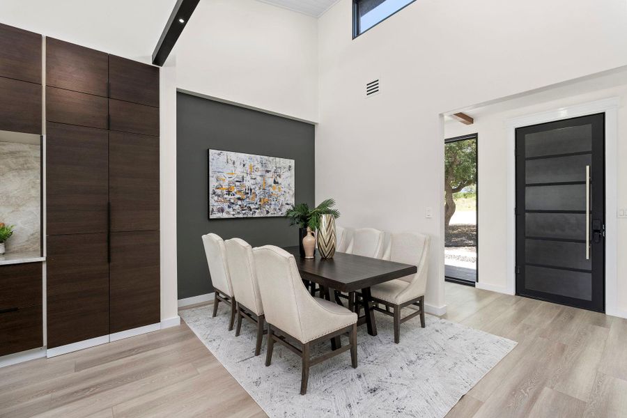 Dining room featuring plenty of natural light, light wood-style floors, and a high ceiling