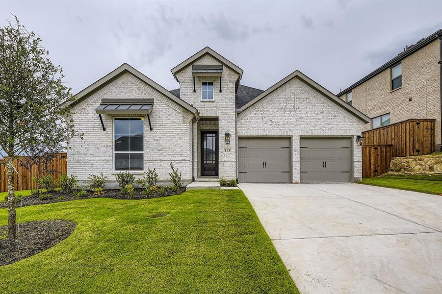 French country style house featuring an attached garage, concrete driveway, and brick siding