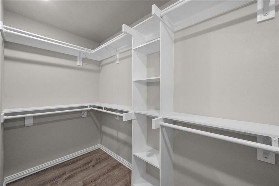 Walk-in closet featuring built-in shelving, multiple hanging rods, and wood-finish flooring