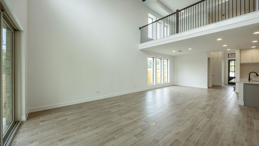 Unfurnished living room featuring a high ceiling, plenty of natural light, wood tiled floors, and recessed lighting Unfurnished living room featuring a high ceiling, plenty of natural light, wood tiled floors, and recessed lighting