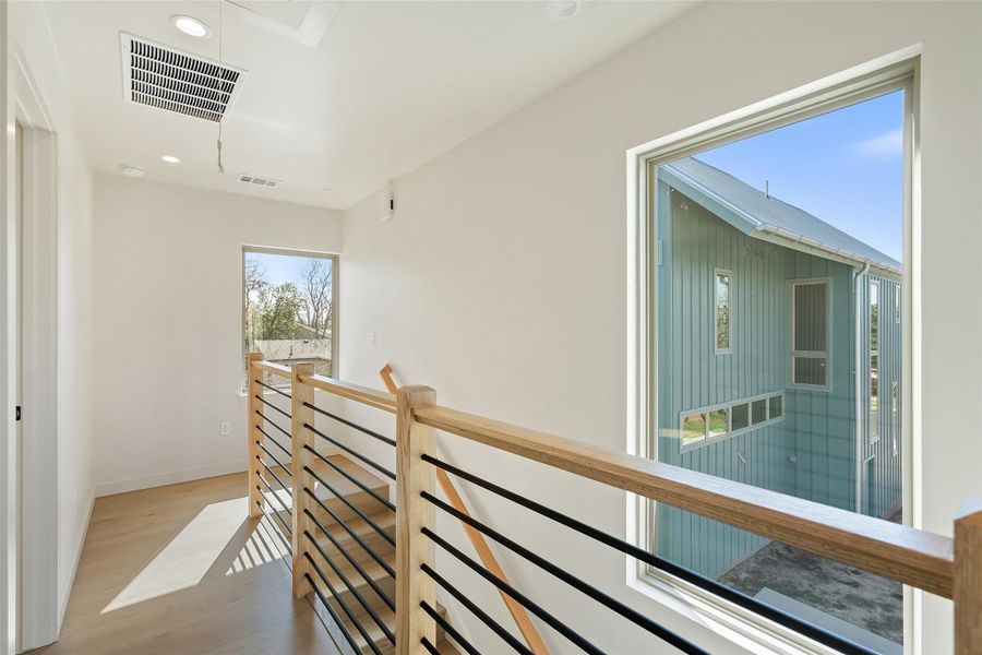 Hall with wood finished floors, an upstairs landing, visible vents, and recessed lighting