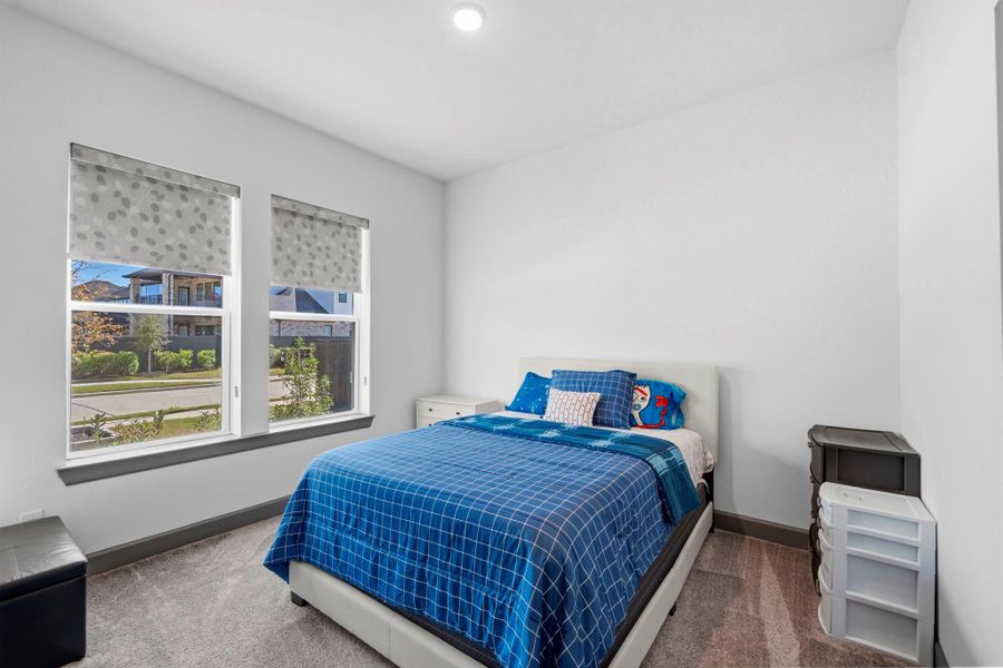Bright secondary bedroom with large windows, abundant natural light, and a clean, comfortable layout.