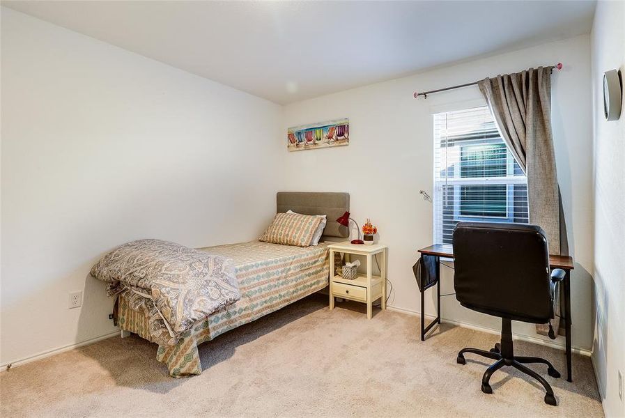 Bedroom with light carpet and an office area