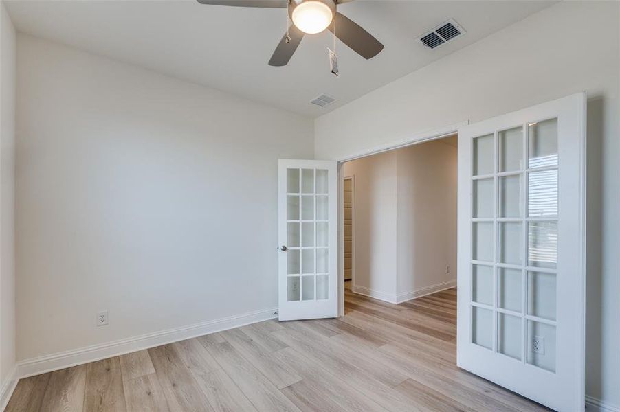Unfurnished room featuring french doors, light wood finished floors, and ceiling fan