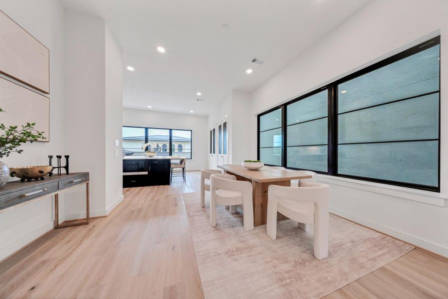 Bright, modern dining area with large windows and light wood flooring. The open layout flows into a sleek kitchen, perfect for entertaining. Bright, modern dining area with large windows and light wood flooring. The open layout flows into a sleek kitchen, perfect for entertaining.