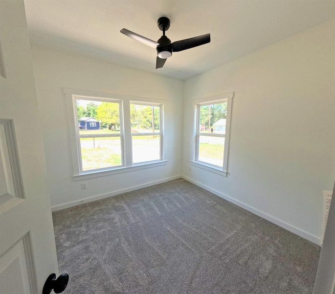 Empty room featuring dark colored carpet and a ceiling fan Empty room featuring dark colored carpet and a ceiling fan