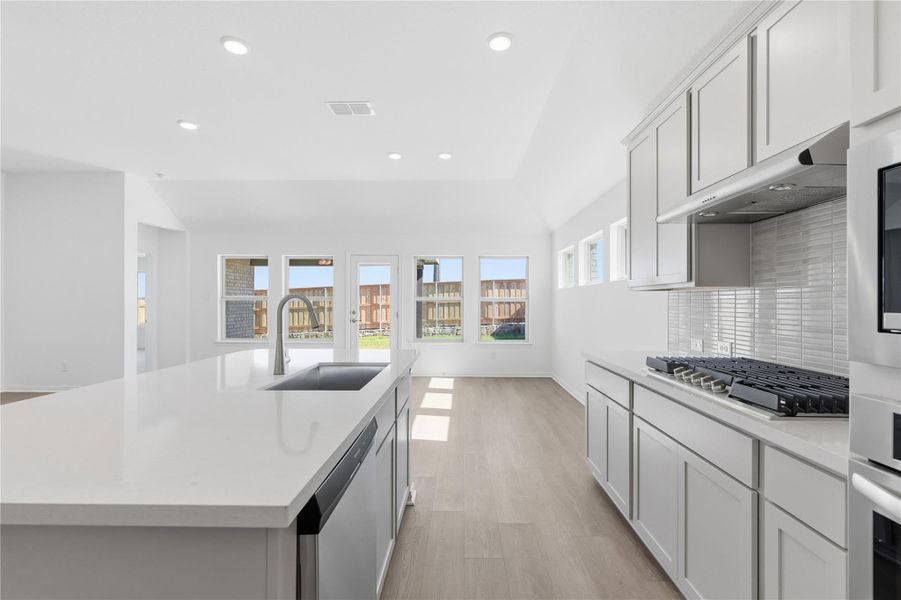 Kitchen featuring recessed lighting, light wood-type flooring, white cabinetry, stainless steel appliances, and light stone countertops