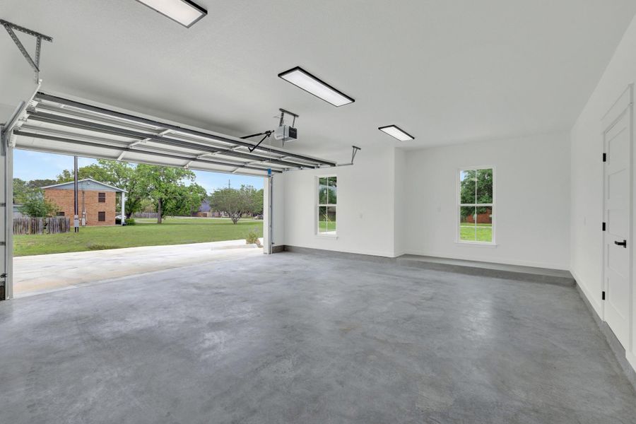 Oversized garage featuring a concrete floor, bright white walls, extra storage and contemporary overhead lighting