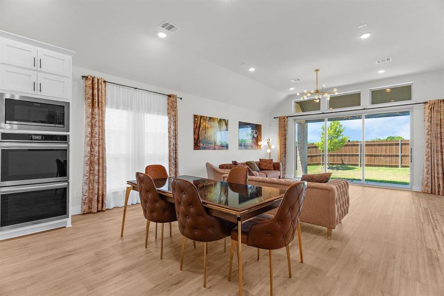 Dining area featuring a chandelier, light wood finished floors, vaulted ceiling, and recessed lighting Dining area featuring a chandelier, light wood finished floors, vaulted ceiling, and recessed lighting