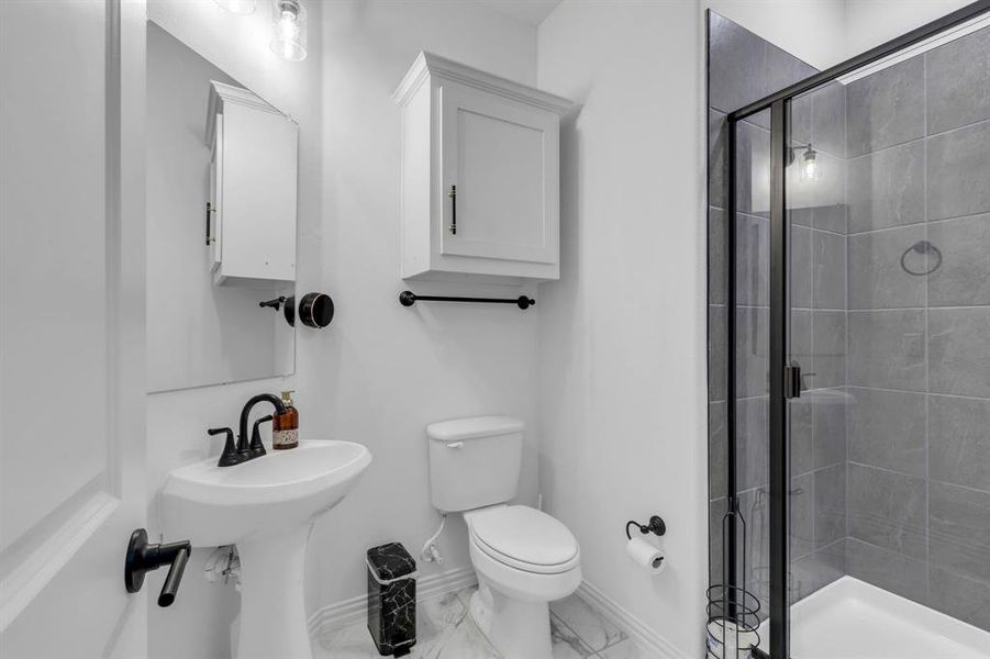 Bathroom with toilet, walk in shower, and tile patterned flooring