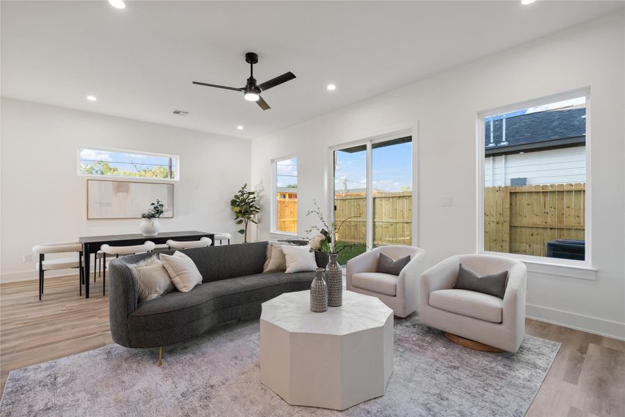This picture-perfect living area is highlighted by expansive windows and sliding doors, flooding the space with natural light. The bright, airy atmosphere enhances the open layout, creating a welcoming and cozy environment. It’s an ideal space for both everyday living and entertaining