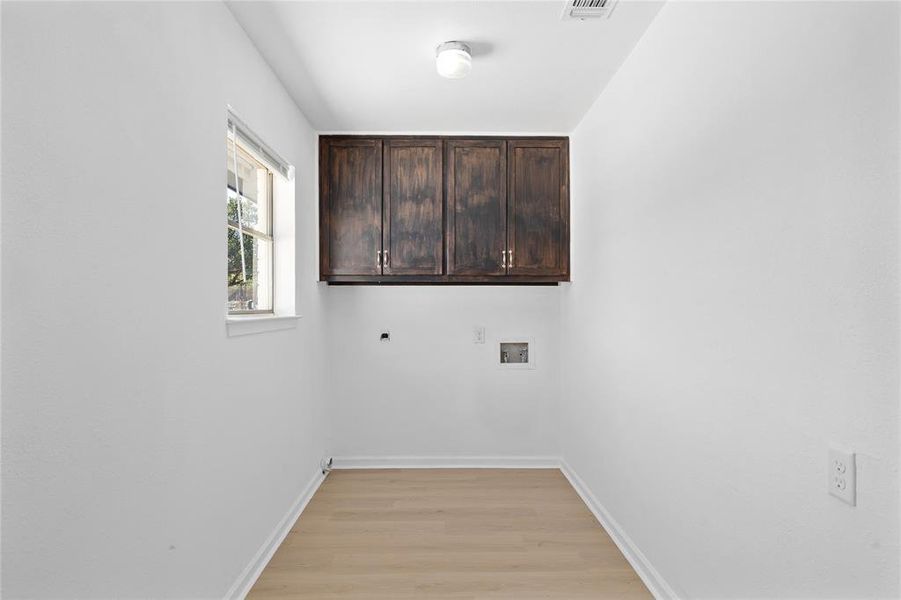 Laundry area featuring cabinet space, light wood finished floors, washer hookup, and electric dryer hookup