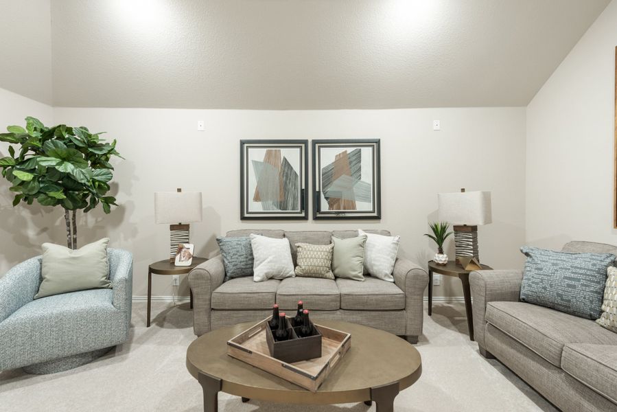 Living room with gray sofa, blue accent chair, round coffee table, and two framed art pieces on the wall