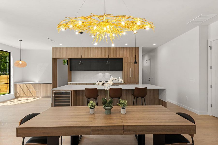 An open floor plan connects the dining space directly to a modern kitchen with minimalist cabinetry.