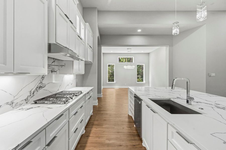 A sleek chef's kitchen pairs dramatic quartz surfaces with a gas cooktop and a generous island with prep sink. The open sightline to the dining area creates a seamless setting for hosting and everyday living.