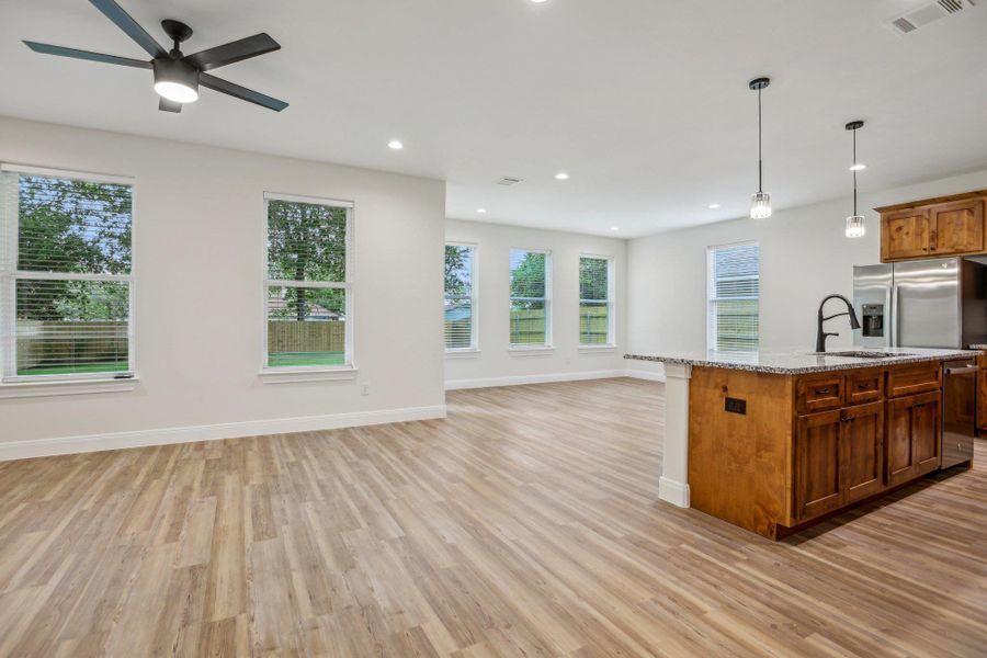 Living Room with light vinyl wood plank floors, a sink, a center island with sink, open floor plan, and visible vents