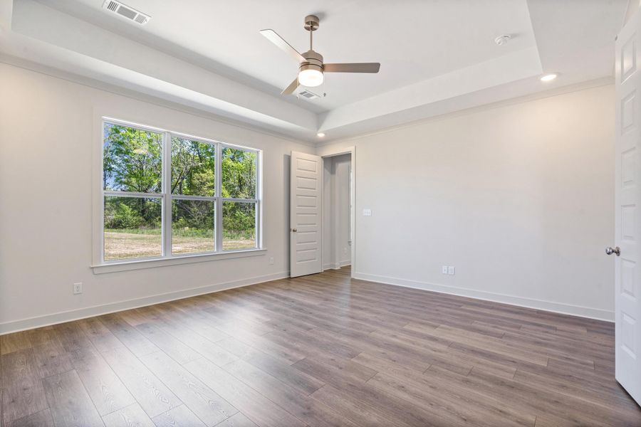 Spare room featuring ceiling fan, a raised ceiling, wood finished floors, and recessed lighting