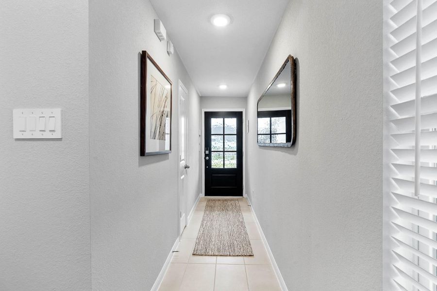 This well-lit entrance hall with recessed lighting provides a smooth, elegant transition from the outside world into the open-concept living areas of the home.