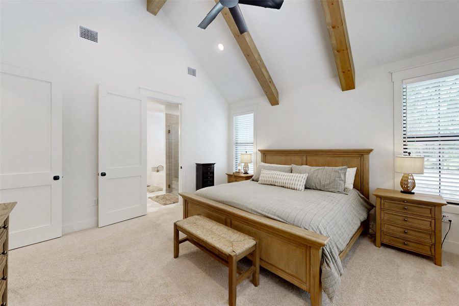 Bedroom with light colored carpet, beam ceiling, ensuite bath, high vaulted ceiling, and a ceiling fan