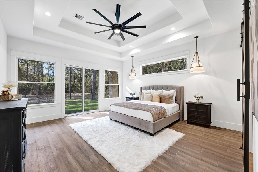 The primary bedroom features a beautifully designed multi-tiered ceiling and custom lighting enhancing the space and ambiance.