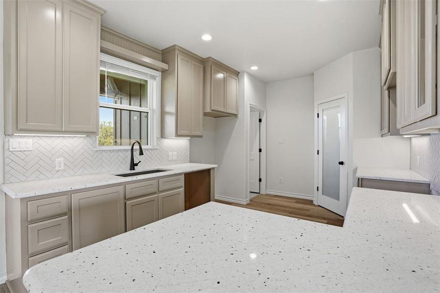 Kitchen with light stone countertops, decorative backsplash, and recessed lighting Kitchen with light stone countertops, decorative backsplash, and recessed lighting