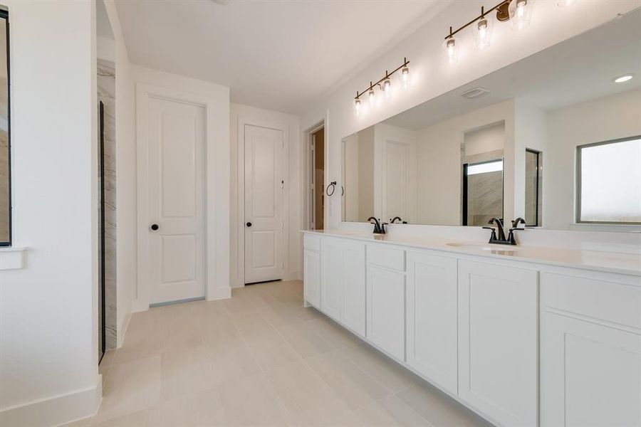 Full bath with double vanity and baseboards