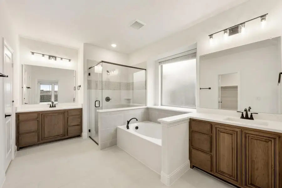 Master bathroom with dual wood vanities, soaking tub, and glass walk-in shower Master bathroom with dual wood vanities, soaking tub, and glass walk-in shower