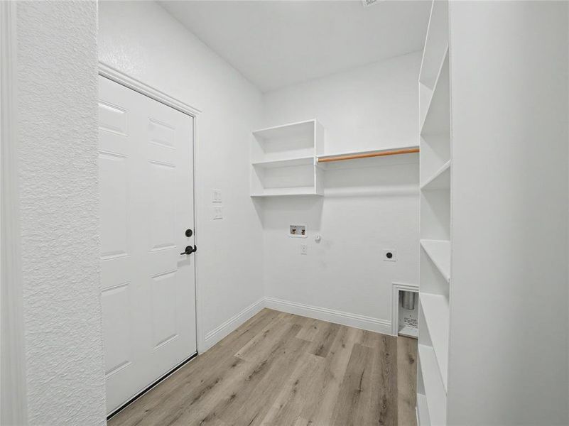 Utility area featuring wood-finish flooring, white walls, and built-in shelving