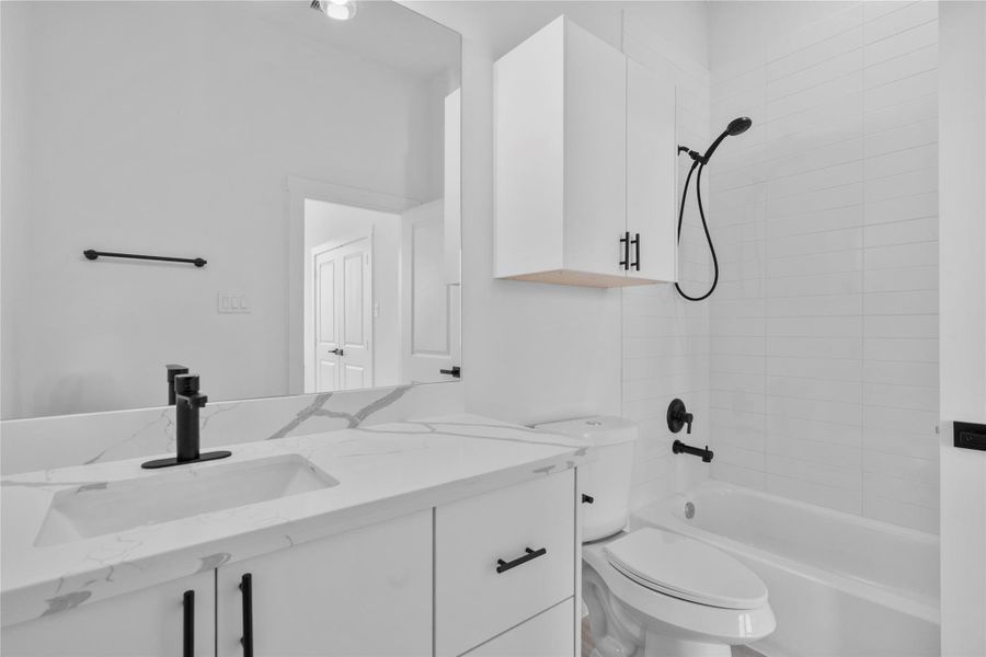 Bathroom featuring quartz countertops and a modern tiled tub/shower combo. Bathroom featuring quartz countertops and a modern tiled tub/shower combo.