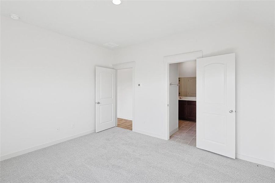 Unfurnished bedroom featuring light colored carpet and ensuite bath