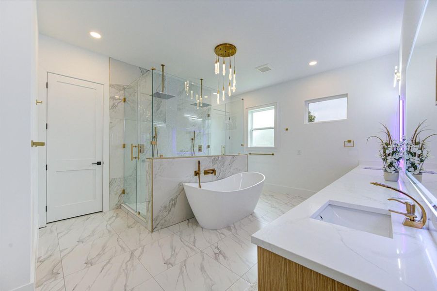 Custom inset cabinets, color-changing LED mirrors, and a stunning chandelier over the soaking tub create a spa-like retreat.