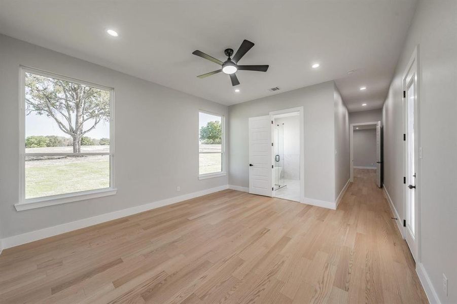 Unfurnished bedroom featuring multiple windows, light wood-type flooring, baseboards, ensuite bathroom, and recessed lighting Unfurnished bedroom featuring multiple windows, light wood-type flooring, baseboards, ensuite bathroom, and recessed lighting
