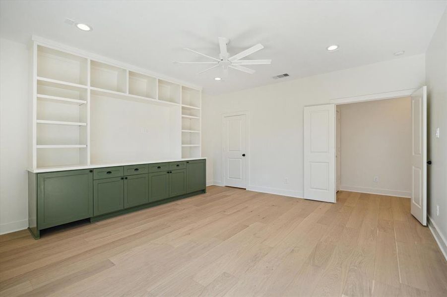 Another angle highlights the thoughtful layout of the game room, showcasing its seamless connection to adjoining spaces. Built-in shelving and cabinetry provide ample storage and display options, while the neutral tones and wood flooring add warmth and versatility to the design.