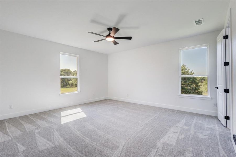 Bright room with white painted walls, gray patterned carpet, a ceiling fan with integrated lighting, and two single-pane windows Bright room with white painted walls, gray patterned carpet, a ceiling fan with integrated lighting, and two single-pane windows